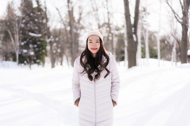 Mulher asiática nova bonita que sorri feliz para o curso na estação do inverno da neve