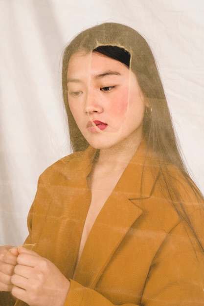 Mulher asiática por trás de tecido transparente