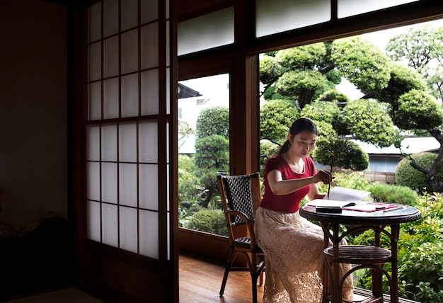 Foto grátis mulher asiática praticando caligrafia japonesa dentro de casa