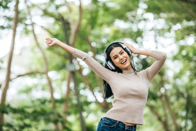 Mulher asiática que escuta música favorita em fones de ouvido. Feliz tempo e relaxe.