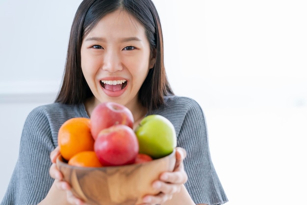 Mulher asiática saudável e bonita sorri felicidade com tigela de dieta de frutas frescas e come o conceito de ideias saudáveis de boa nutrição