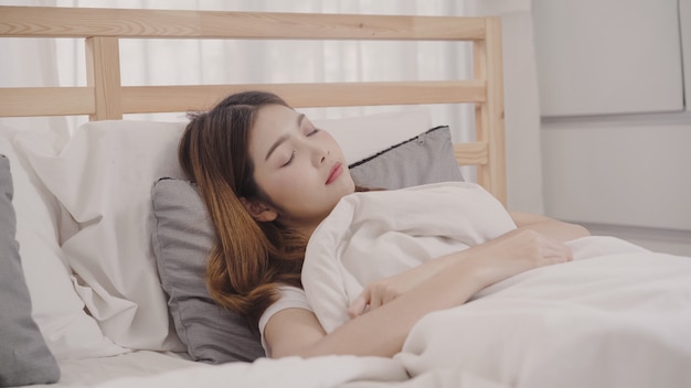 Mulher asiática sonhando enquanto dorme na cama no quarto