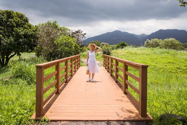 Mulher asiática sorridente caminhando na natureza em um dia nublado