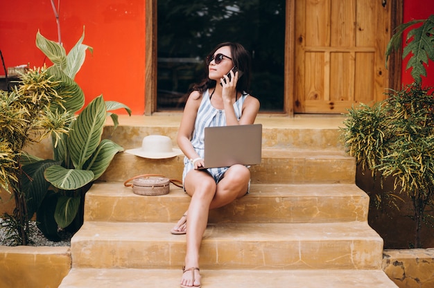 Mulher asiática trabalhando no laptop em um período de férias e sentado nas escadas