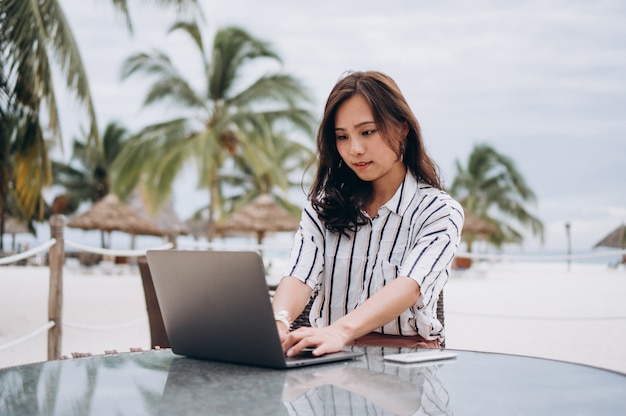 Foto grátis mulher asiática trabalhando no laptop em um período de férias