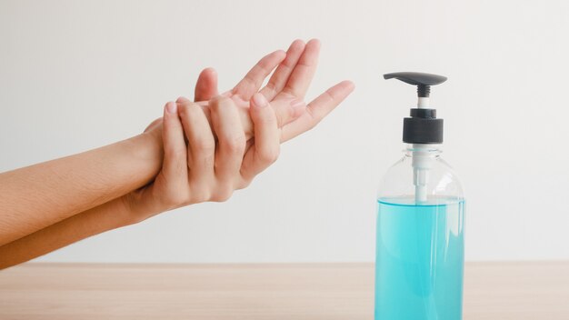 Mulher asiática usando álcool gel desinfetante para as mãos lavar a mão para proteger o coronavírus. Garrafa de álcool de pressão feminina para limpar as mãos para higiene quando o distanciamento social fica em casa e o tempo de quarentena.
