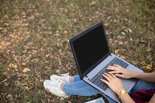 Mulher asiática usando máscara facial olhando para um laptop