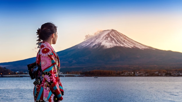 Foto grátis mulher asiática vestindo quimono tradicional japonês na montanha fuji. pôr do sol no lago kawaguchiko, no japão.