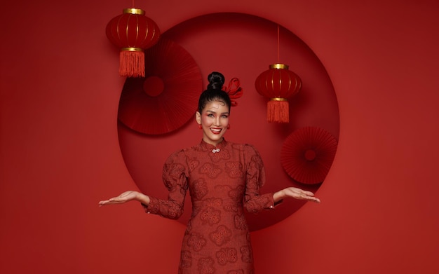 Foto grátis mulher asiática vestindo vestido tradicional cheongsam qipao com gesto de boas-vindas ao ano novo chinês de 2024