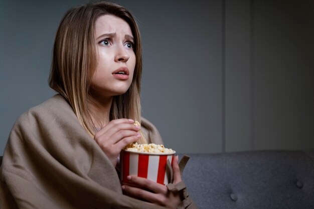 Mulher assistindo tv e comendo pipoca