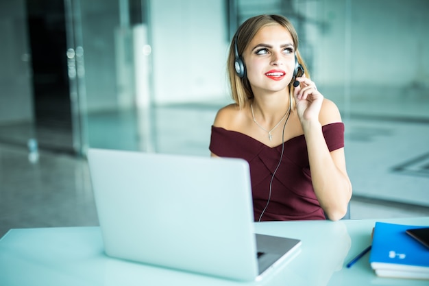 Foto grátis mulher atenta e focada em fones de ouvido senta na mesa com laptop, olha para a tela, faz anotações, aprende língua estrangeira na internet, curso de estudo online autoeducação na web consulta cliente por vídeo