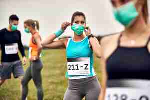 Foto grátis mulher atlética se preparando para uma maratona e colocando máscara facial protetora na natureza