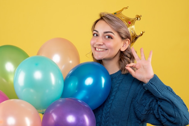 mulher atraente com balões coloridos em coroa em amarelo