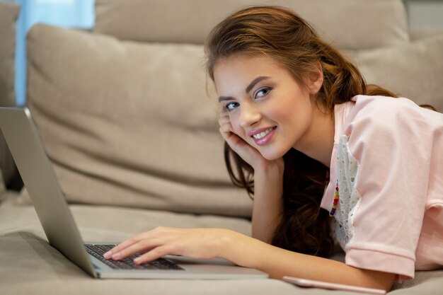Mulher atraente com laptop em casa. Jovem mulher trabalhando no computador enquanto está sentado em casa. Aproveitando o tempo em casa.