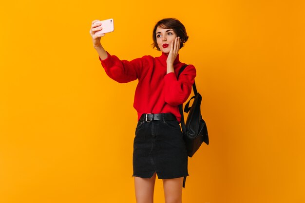 Mulher atraente com mochila tirando selfie