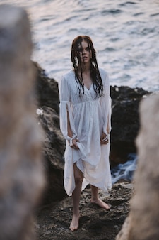 Mulher atraente de vestido branco na natureza da praia do mar