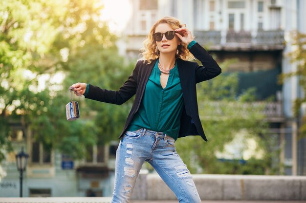 Mulher atraente e elegante andando na rua da cidade com bolsa, vestindo jaqueta preta, confiante e sexy,