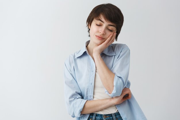 Mulher atraente e elegante fechando os olhos e apoiando-se na palma da mão para tirar uma soneca, dormindo