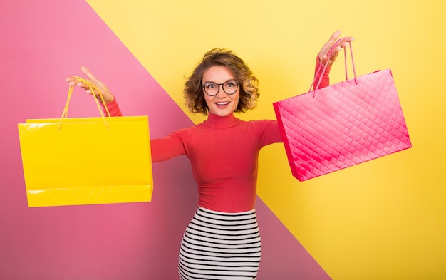 Mulher atraente em uma roupa elegante e colorida segurando sacolas de compras