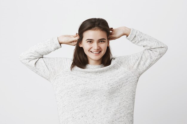 mulher atraente, esticando e tocando o cabelo dela enquanto sorrindo amplamente