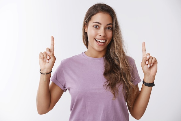 Mulher atraente feliz apontando o dedo para cima