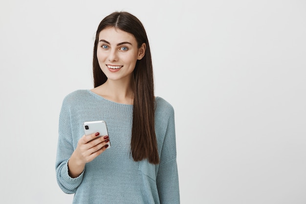 Mulher atraente feliz sorrindo com telefone celular