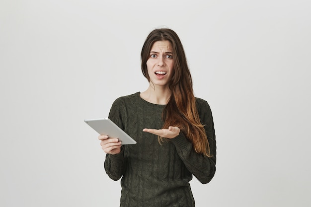 Mulher atraente jovem decepcionada, reclamando de algo no tablet digital