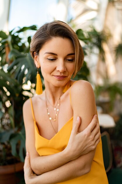 Mulher atraente no vestido de verão amarelo na sala interior de estilo boho