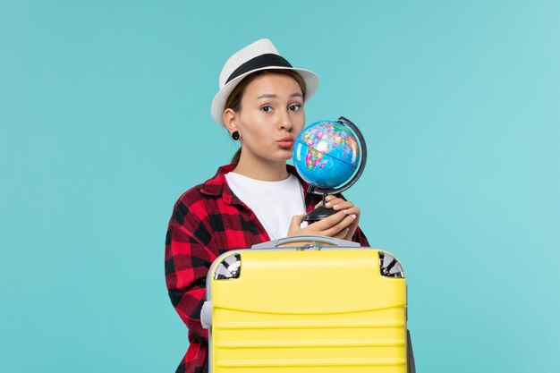 Mulher atraente segurando o globo de frente e se preparando para uma viagem no espaço azul