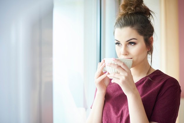 Mulher atraente tomando café dentro de casa