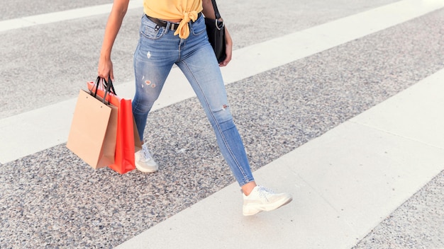 Mulher atravessando a rua com sacolas de compras