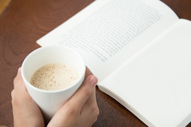 Mulher bebendo café e livro de leitura