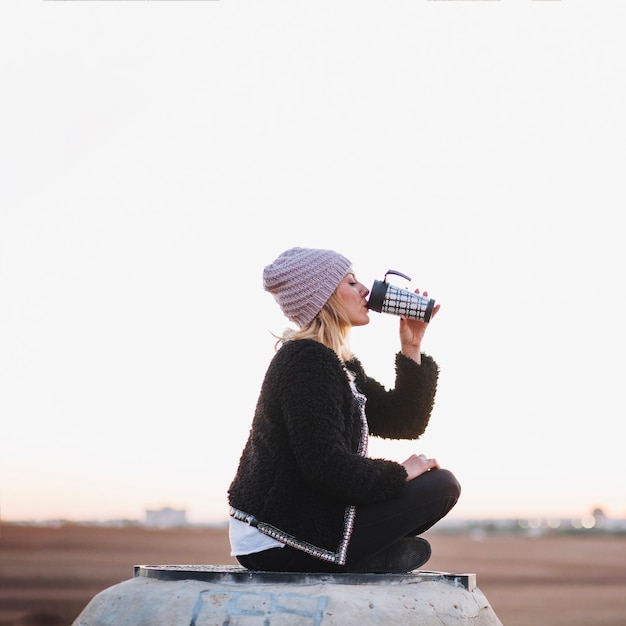 Foto grátis mulher bebendo de thermos na natureza