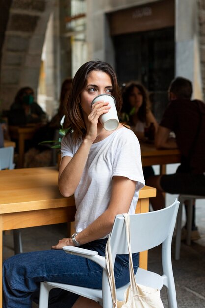 Foto grátis mulher bebendo de um recipiente sustentável