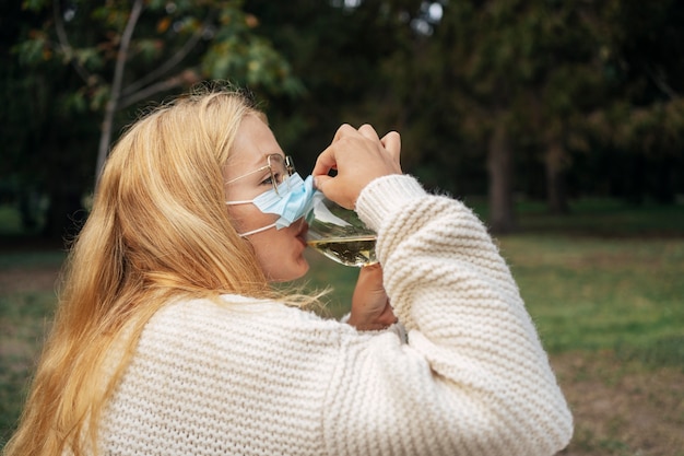 Mulher bebendo vinho com máscara facial