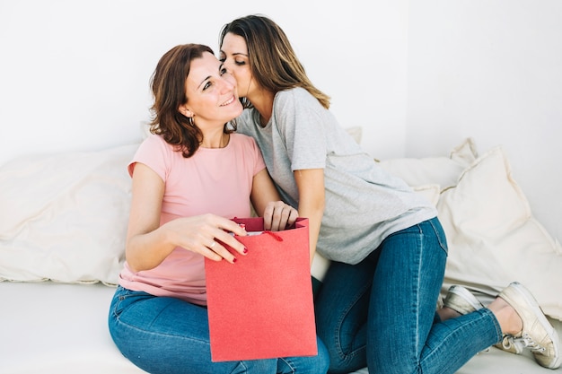 Foto grátis mulher beijando mulher com saco de papel vermelho