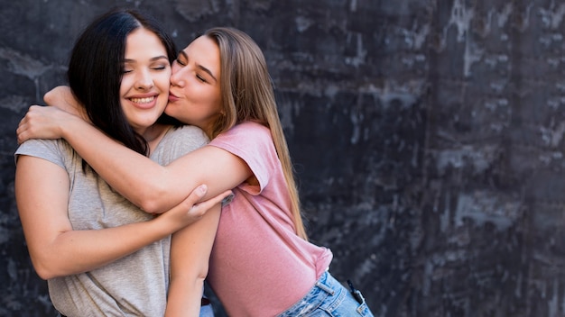 Mulher beijando sua melhor amiga na bochecha com espaço de cópia