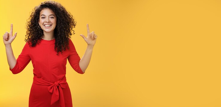 Foto grátis mulher bem-sucedida alegre e amigável despreocupada com penteado encaracolado em vestido vermelho sorrindo encantado