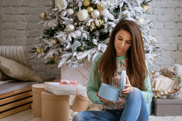 Mulher bonita abre presentes em casa na árvore de Natal