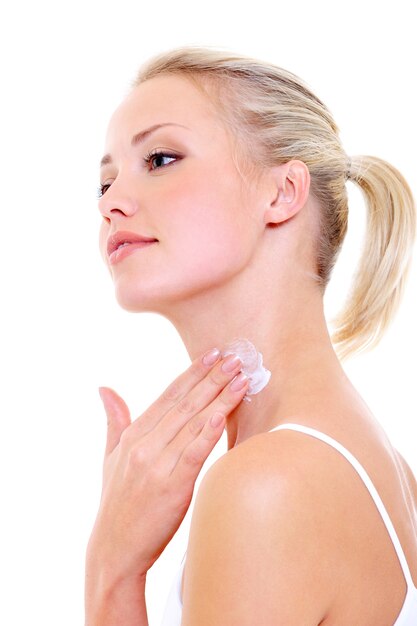 Mulher bonita aplicando creme hidratante no pescoço - isolado no branco