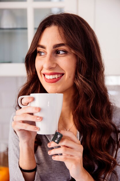 Mulher bonita bebendo chá na cozinha