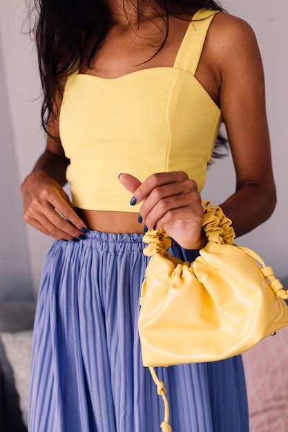 Mulher bonita blogueira de moda vestindo blusa amarela e calça roxa
