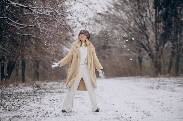 Mulher bonita caminhando em um parque cheio de neve