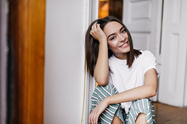 Mulher bonita caucasiana com sorriso fofo, posando em casa no fim de semana. Mulher morena encantadora relaxando