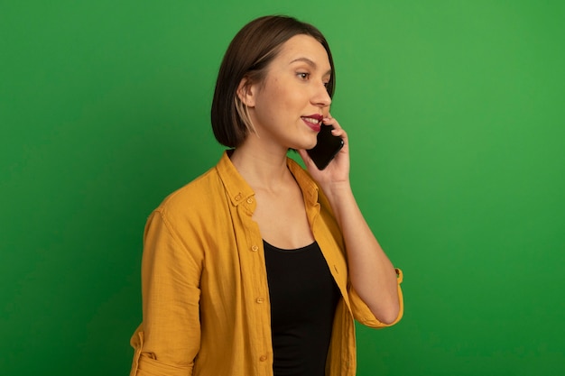 Mulher bonita caucasiana confiante parada de lado, falando no telefone no verde