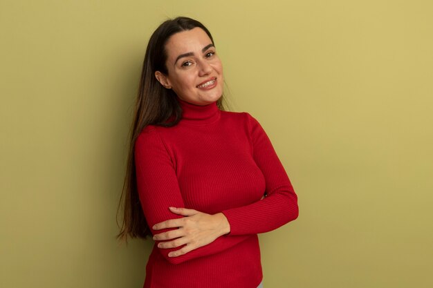 Mulher bonita caucasiana sorridente em pé com os braços cruzados na cor verde oliva