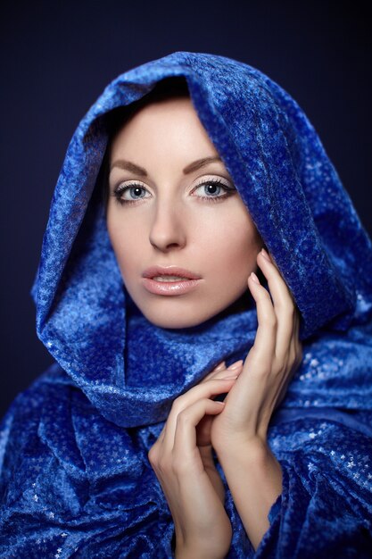 Mulher bonita closeup retrato maquiagem brilhante no pano de cor azul isolado no escuro