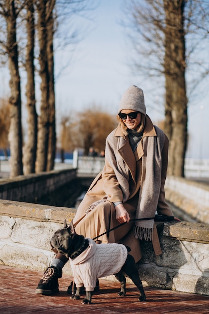 Mulher bonita com buldogue francês andando no parque