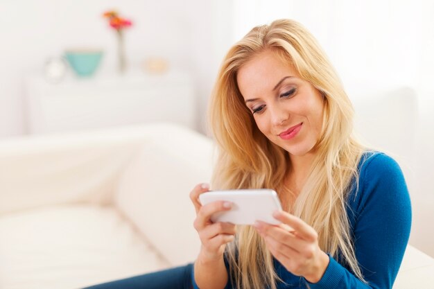 Mulher bonita com celular branco na sala de estar