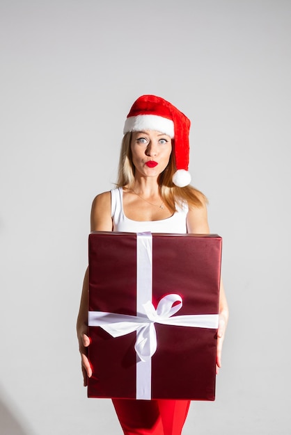 Mulher bonita com chapéu de natal vermelho e branco segurando um grande presente